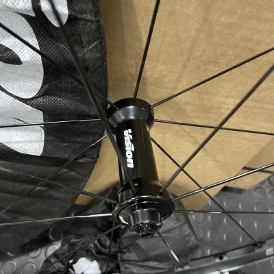 Roda de bicicleta preta com cubo Vision e raios metálicos em fundo de tecido preto