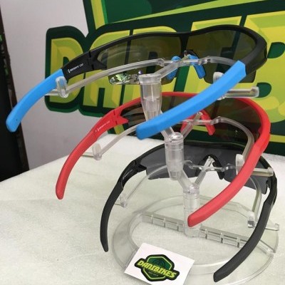 Óculos desportivos com hastes coloridas expostos num suporte transparente