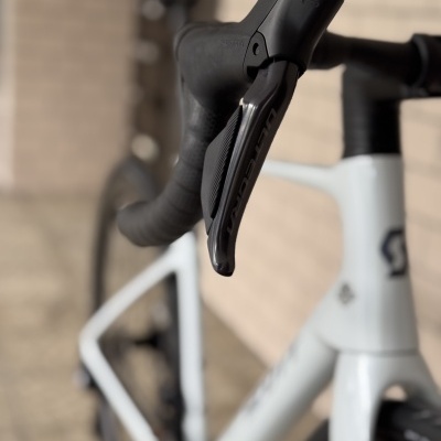 Guiador de bicicleta de estrada preto com manete Shimano Ultegra num quadro branco.