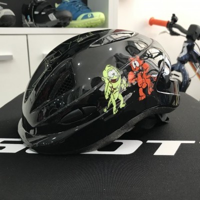 Capacete preto para bicicleta com desenhos animados e texto SCOTT em fundo preto