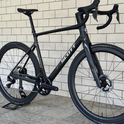 Bicicleta de estrada preta com quadro de carbono e marca SCOTT