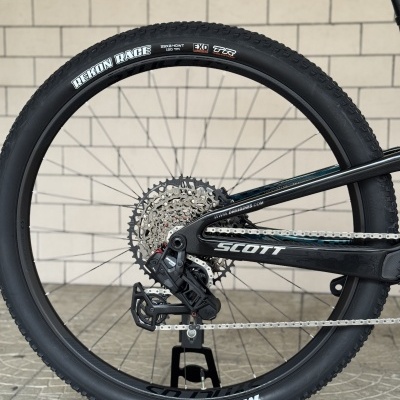 Roda de bicicleta de montanha com pneu Maxxis preto, aro preto e engrenagem metálica.