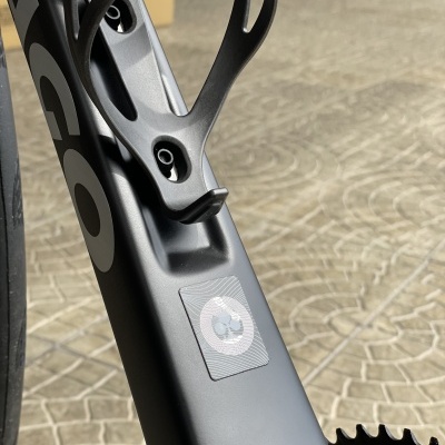 Suporte para garrafa em bicicleta preta com autocolante cinza e branco no quadro sobre calçada