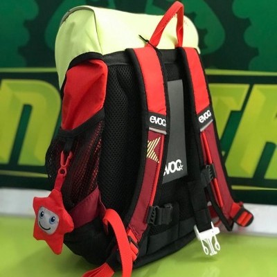 Mochila preta, vermelha e amarela com chaveiro de estrela sorridente.