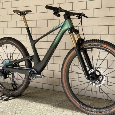 Bicicleta de montanha cinza e verde com pneus castanho claro encostada a parede