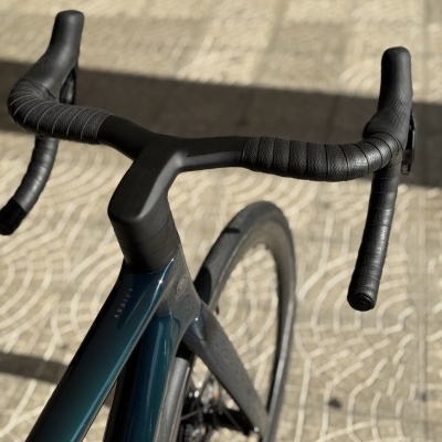 Guiador de bicicleta de estrada preto e quadro azul escuro em piso de pedra