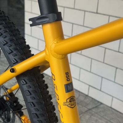 Quadro de bicicleta amarelo fosco com pneus pretos e texto de marca