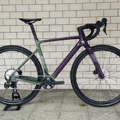 Bicicleta de estrada verde e roxa com pneus pretos e componentes Shimano GRX