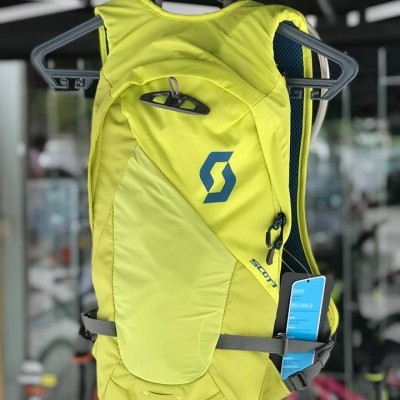 mochila de hidratação verde-limão da marca SCOTT pendurada num cabide