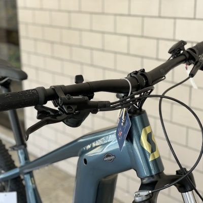 Bicicleta de montanha azul com guiador preto encostada a parede de tijolos