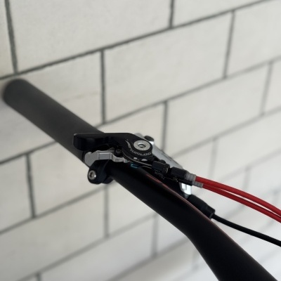 Punho preto de guiador de bicicleta com manete de travão e cabos vermelhos