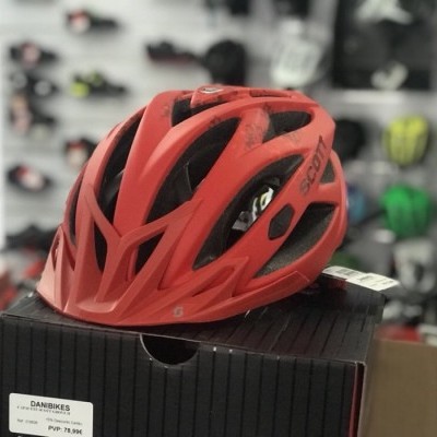Capacete de ciclismo vermelho sobre caixa preta em loja de bicicletas