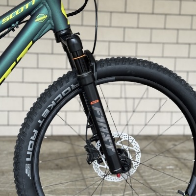 Bicicleta de montanha verde escuro com suspensão dianteira preta e roda com pneu Schwalbe Rocket Ron