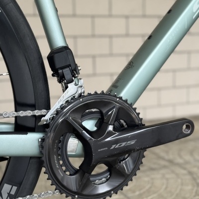 Detalhe de quadro e pedaleira de bicicleta Shimano 105 preta com quadro verde-acinzentado