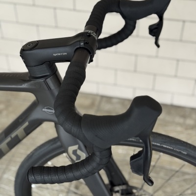 Guiador de bicicleta de estrada preto com fita preta e manetes integradas