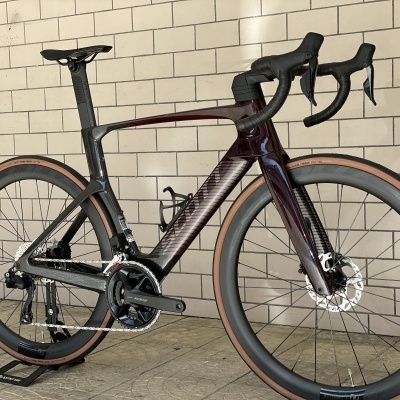 Bicicleta de estrada preta e vinho com pneus castanhos e guiador curvo