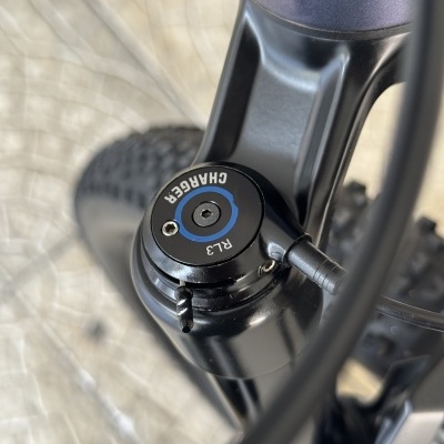 Detalhe de suspensão de bicicleta preta com texto Charger RL3 e pneu texturado.