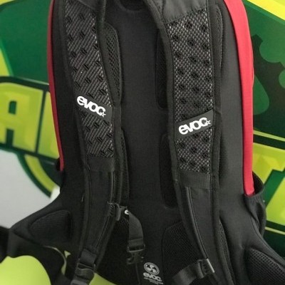 mochila preta e vermelha com alças acolchoadas e etiquetas EVOC
