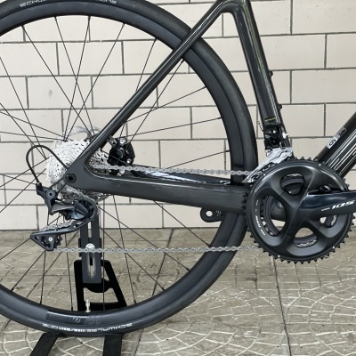 Bicicleta de estrada preta com roda traseira e componentes Shimano Ultegra em fundo de azulejos