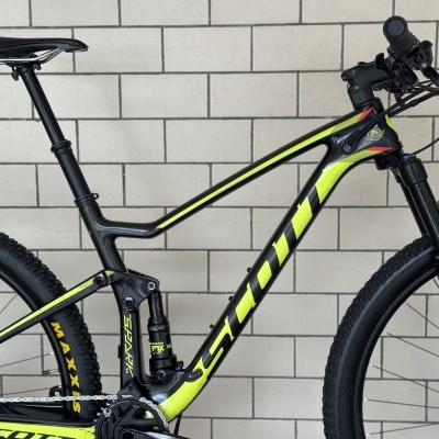 Bicicleta de montanha preta e amarelo fluorescente encostada numa parede de azulejos