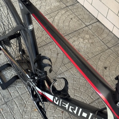 Bicicleta de estrada preta com detalhes vermelhos e brancos sobre piso de lajes cinzentas