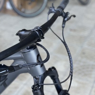 Guiador preto e quadro cinza de bicicleta off-road com pneus grossos em piso de calçada