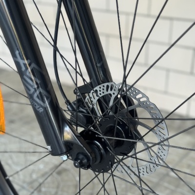 Roda dianteira de bicicleta preta com disco de travão perfurado e raios finos