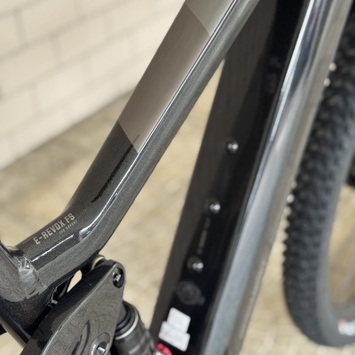Quadro de bicicleta preto e cinzento com suspensão traseira e pneu com cravos largos.
