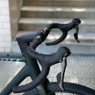 Bicicleta verde escura com guidão drop preto e pneus rugosos