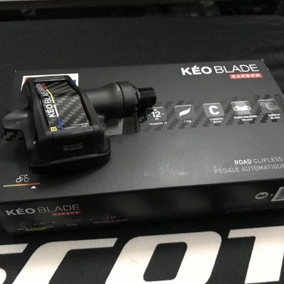 Pedal de bicicleta KÉO BLADE Carbon sobre caixa preta com texto e ícones explicativos.