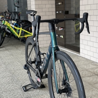 Bicicleta de estrada preta e azul esverdeada com guiador drop numa área coberta