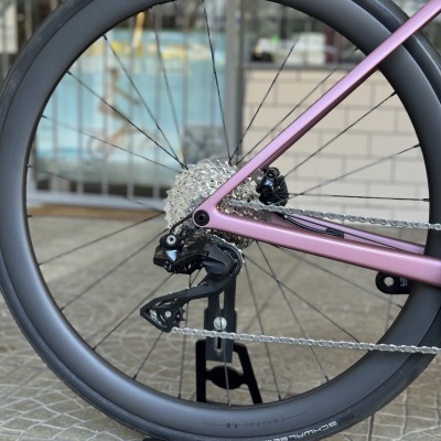 Roda traseira de bicicleta com aro preto fosco e quadro rosa em suporte preto
