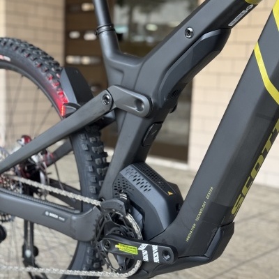 Detalhe de bicicleta elétrica preta e amarela com motor Bosch e pneus Maxxis