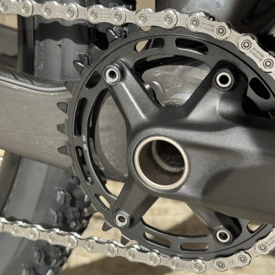 Pedalier de bicicleta preto com corrente prateada Shimano sobre pavimento de pedra