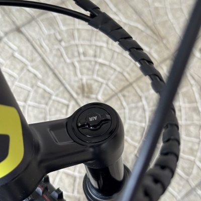 Tubo de suspensão de bicicleta preta com cabos pretos e chão de pedras claras