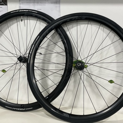 Dupla de rodas de bicicleta pretas com cubos verdes apoiadas em parede branca