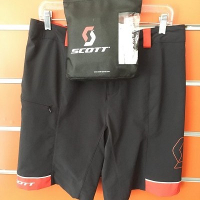 Calções pretos com detalhes vermelhos e logotipo SCOTT pendurados em cabides