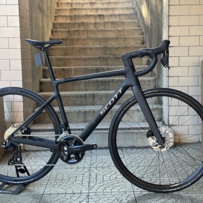 Bicicleta de estrada Scott preta montada em ambiente interno com caixas de cartão ao fundo