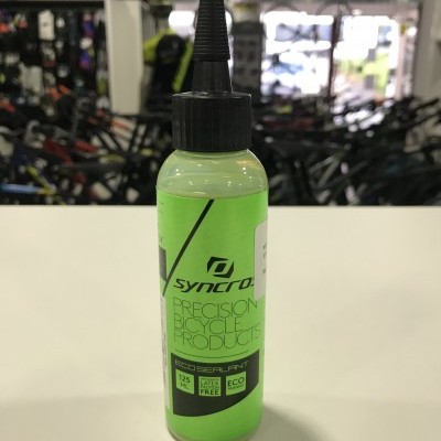 Frasco verde claro de selante para bicicletas Syncros numa loja de bicicletas