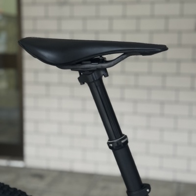 Selim de bicicleta preto com poste e pneu contra fundo de parede branca