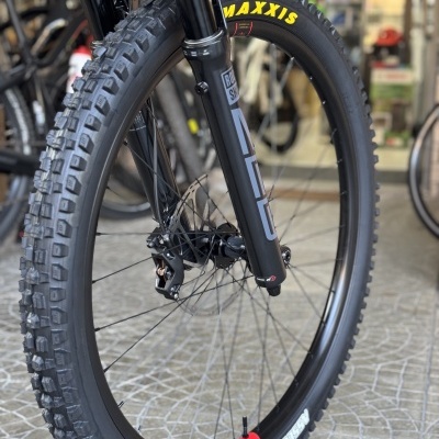 Pneu de bicicleta preto MAXXIS com letra amarela em roda com suspensão ROCK SHOX SID