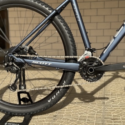Quadro de bicicleta azul escuro com texto SCOTT e ASPECT, roda com pneu KENDA e chão pavimentado