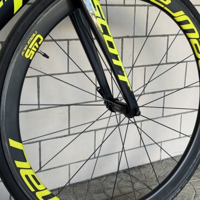 Roda de bicicleta de carbono preta e amarela no chão em azulejos brancos