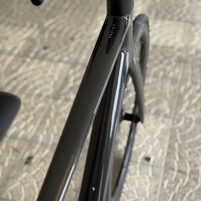 Bicicleta de estrada cinza escuro com roda traseira aero e piso de mosaico claro