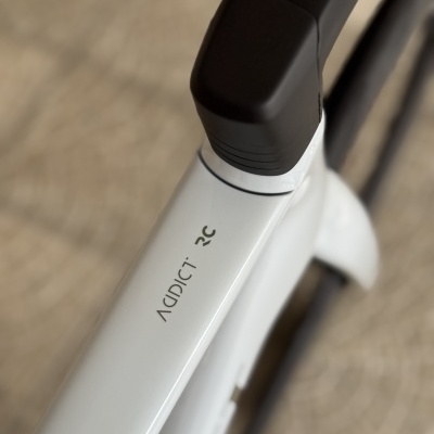 Tubo superior branco de bicicleta com texto 'ADDICT 12C' e suporte do guiador preto