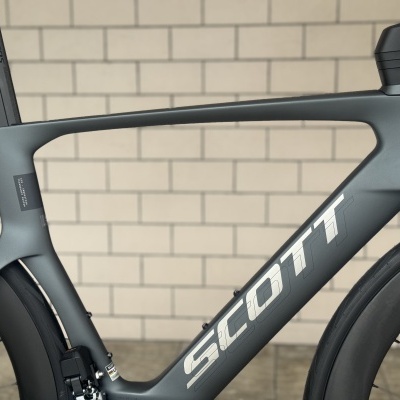 Quadro de bicicleta Scott cinza fosco em carbono com texto branco e rodas pretas aerodinâmicas