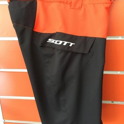 Calções bicolores em tecido técnico preto e laranja com logo SCOTT pendurados