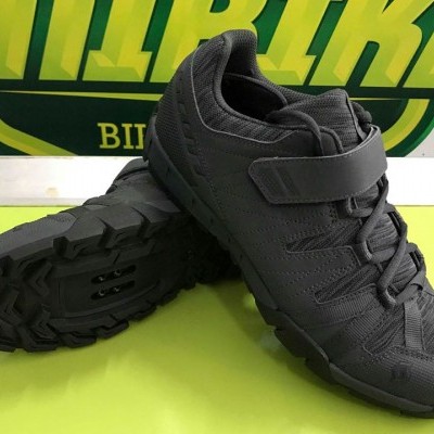 Sapatilhas desportivas pretas com velcro e sola antiderrapante numa superfície verde