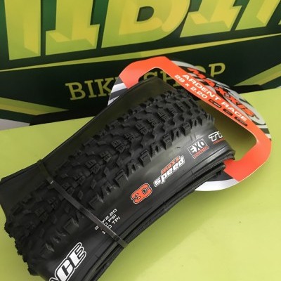 Pneu MTB preto com etiquetas 29x2.25, 3C MaxxSpeed, EXO Protex e Race Face num fundo amarelo e verde