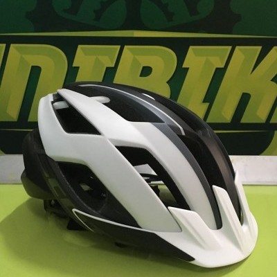 Capacete de ciclismo branco e preto sobre superfície verde com fundo 'DIRBIK'